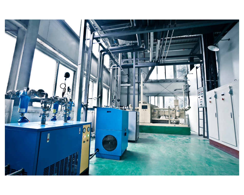 intérieur d'un bâtiment avec tuyauterie au plafond et blocs bleus et appareils électriques dans une usine